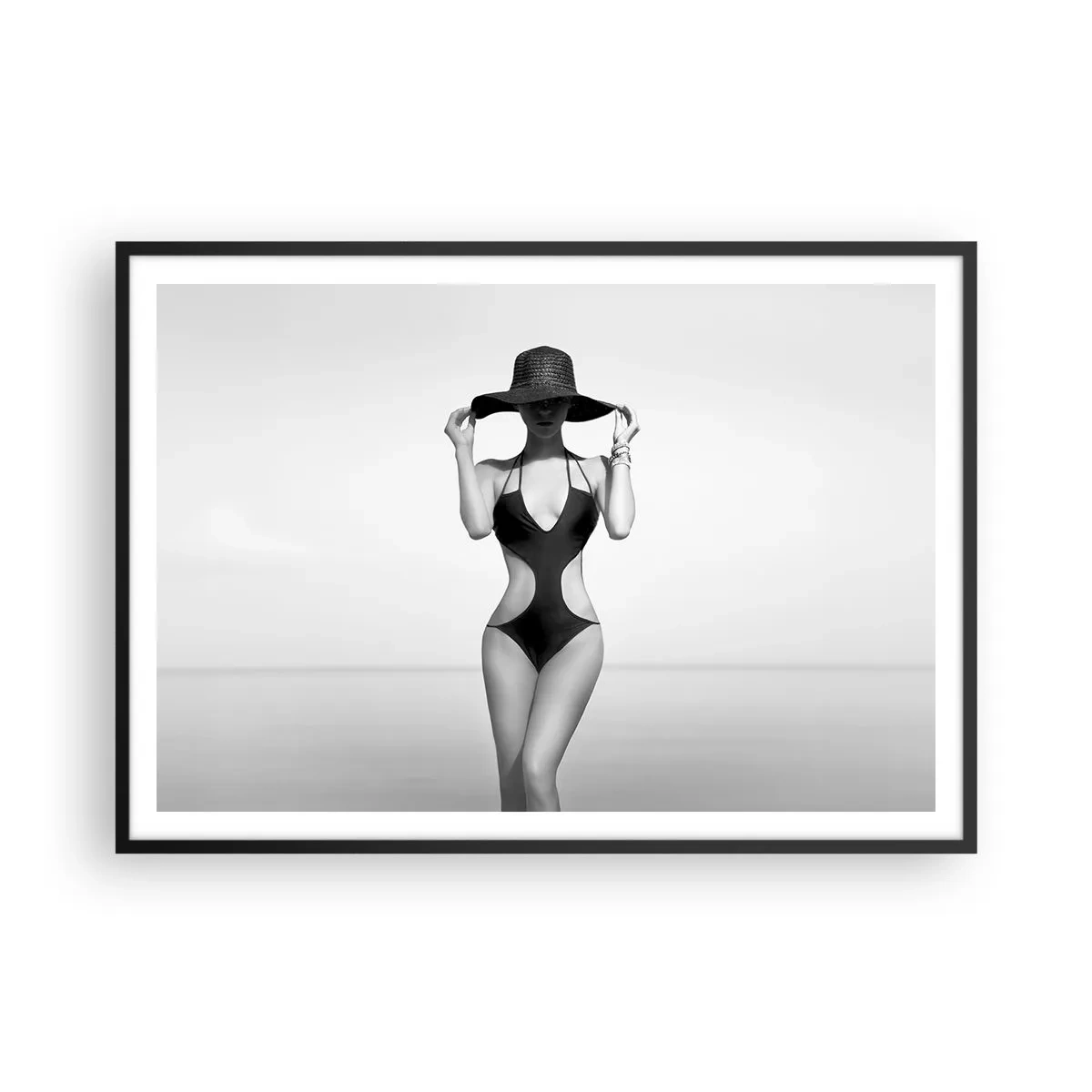 Poster in einem schwarzem Rahmen - Schwarz-weiße Silhouette einer Frau mit Hut vor dem Meereshintergrund - 100x70cm - Mein Name ist: Eleganz - Moderne Wanddekoration für Wohnzimmer und Schlafzimmer ARTTOR