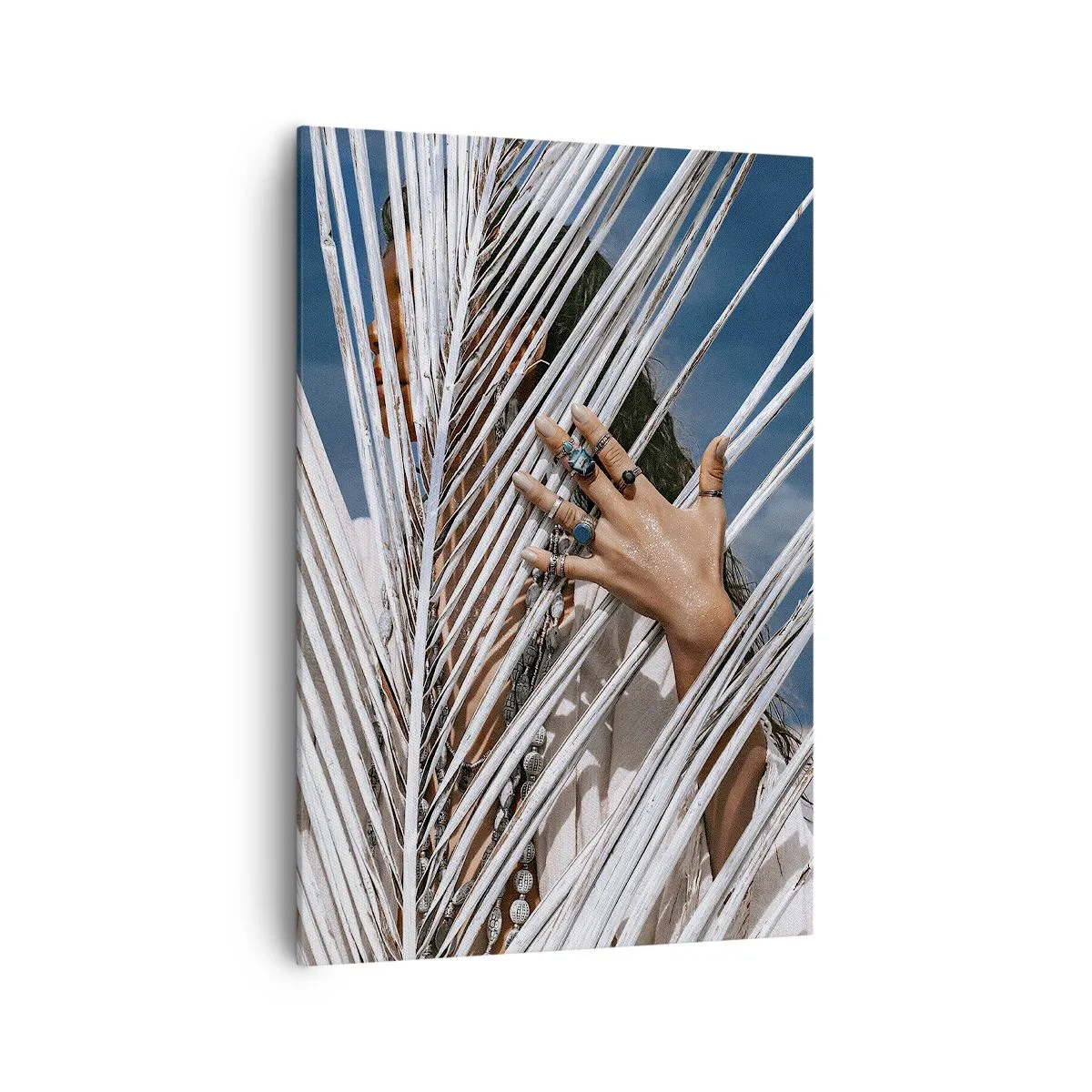 Bild auf Leinwand - Leinwandbild - Eine Frau, versteckt hinter Palmblättern, mit Ringen an den Händen. - 70x100cm - Das Mädchen des Schamanen? - Moderne Wanddekoration für Wohnzimmer und Schlafzimmer ARTTOR
