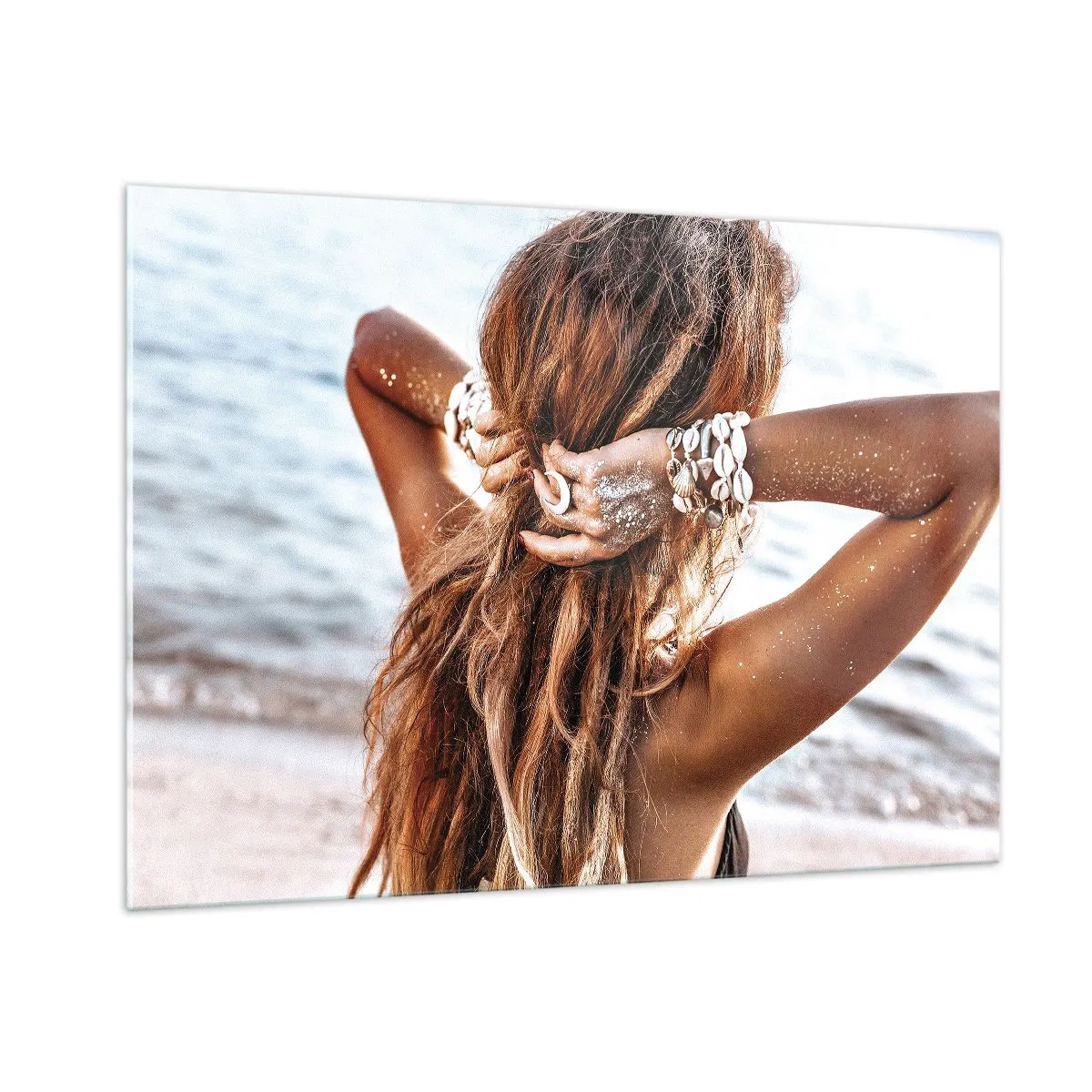 Glasbild - Bild auf glas - Eine Frau mit langen Haaren am Strand, umgeben von Muscheln und Sand. - 100x70cm - Eine Schwester von Wasser und Sonne - Moderne Wanddekoration für Wohnzimmer und Schlafzimmer ARTTOR