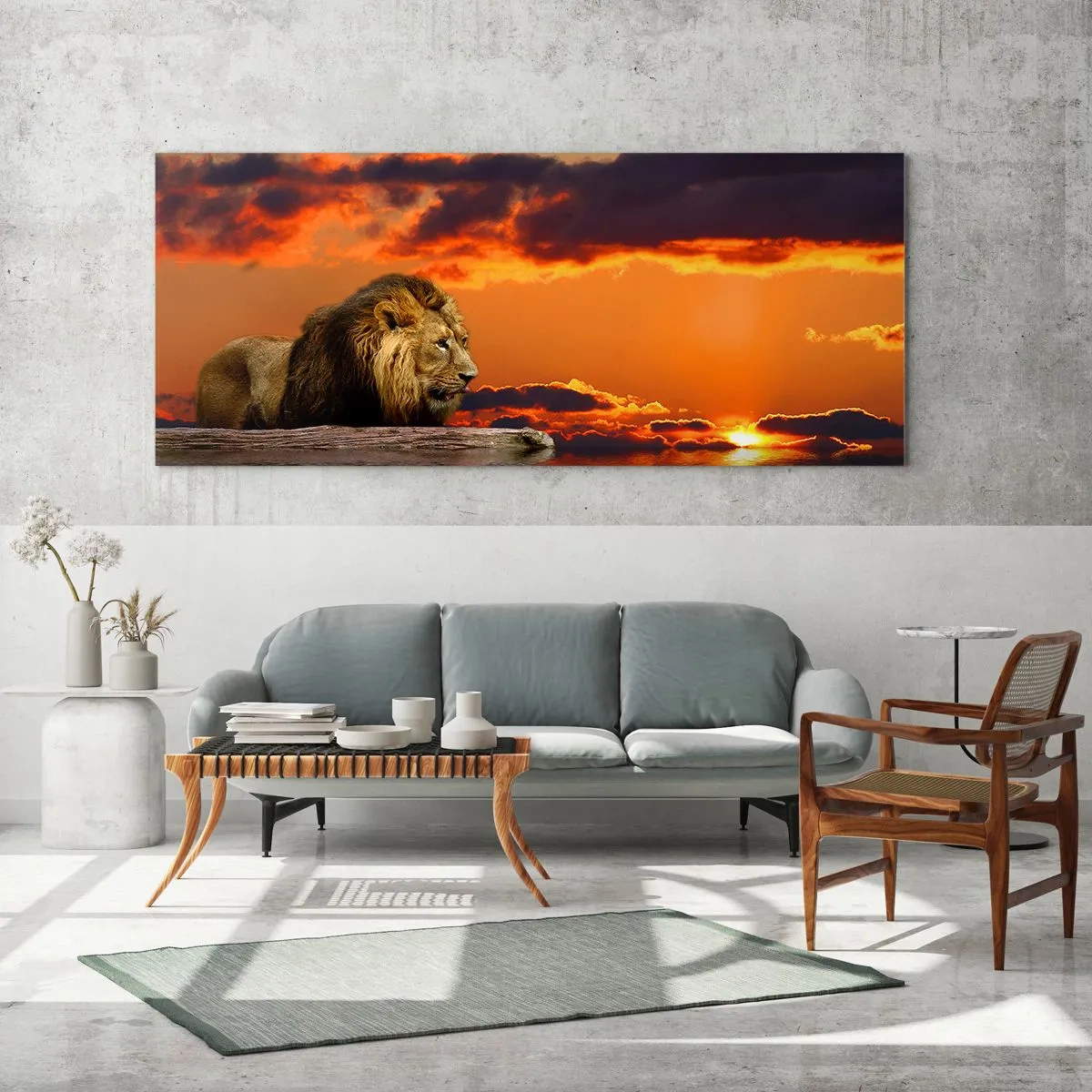 Glasbild - Bild auf glas - Ein Löwe ruht bei Sonnenuntergang vor einem dramatischen Himmel am Wasser. - 140x50cm - König der Natur - Moderne Wanddekoration für Wohnzimmer und Schlafzimmer ARTTOR