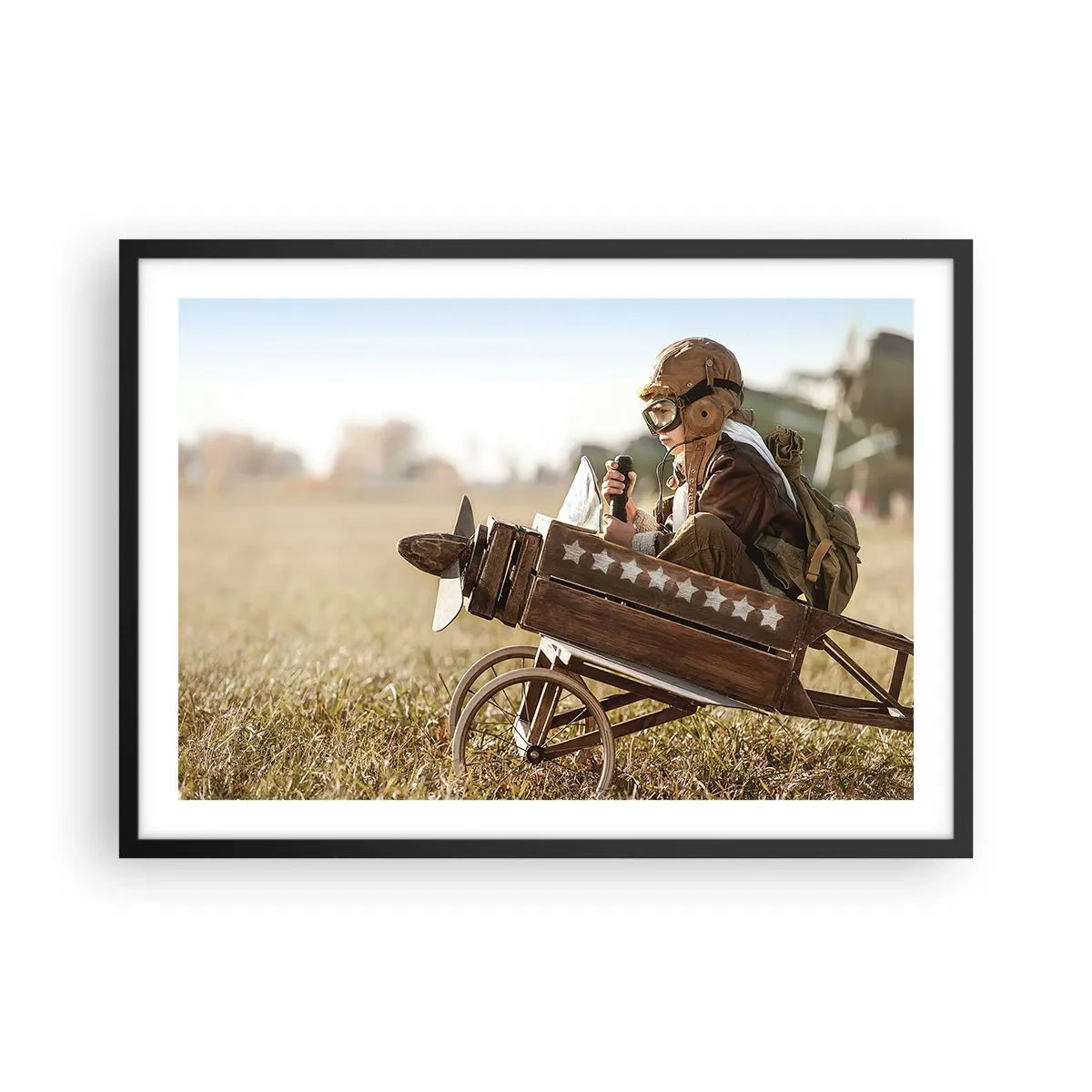 Poster in einem schwarzem Rahmen - Ein Kind in einem Spielzeugflugzeug mit einem Feld im Hintergrund - 70x50cm - Start in Richtung eines Traums - Moderne Wanddekoration für Wohnzimmer und Schlafzimmer ARTTOR