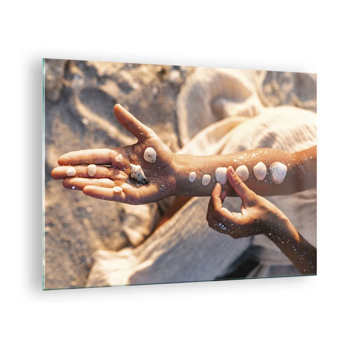 Glasbild - Bild auf glas - Kinderhände mit Muscheln auf einem Hintergrund aus Sand und Stoff - 70x50cm - Schönheit an Ihren Fingerspitzen - Moderne Wanddekoration für Wohnzimmer und Schlafzimmer ARTTOR