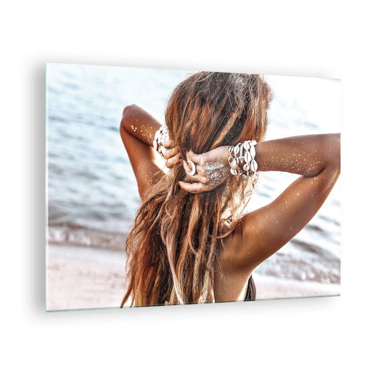 Glasbild - Bild auf glas - Eine Frau mit langen Haaren am Strand, umgeben von Muscheln und Sand. - 70x50cm - Eine Schwester von Wasser und Sonne - Moderne Wanddekoration für Wohnzimmer und Schlafzimmer ARTTOR