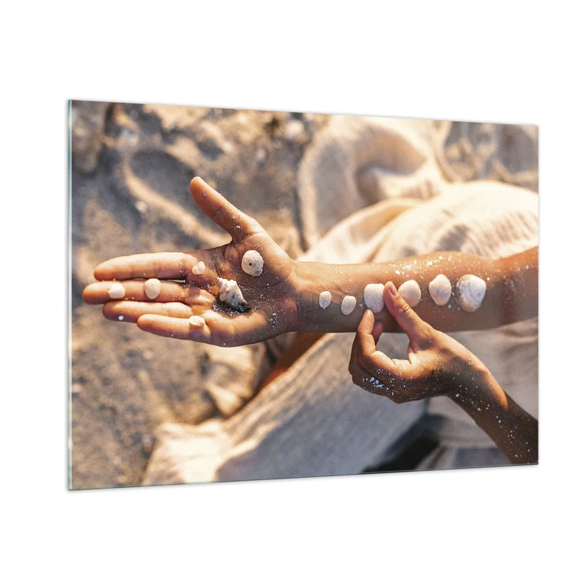 Glasbild - Bild auf glas - Kinderhände mit Muscheln auf einem Hintergrund aus Sand und Stoff - 100x70cm - Schönheit an Ihren Fingerspitzen - Moderne Wanddekoration für Wohnzimmer und Schlafzimmer ARTTOR