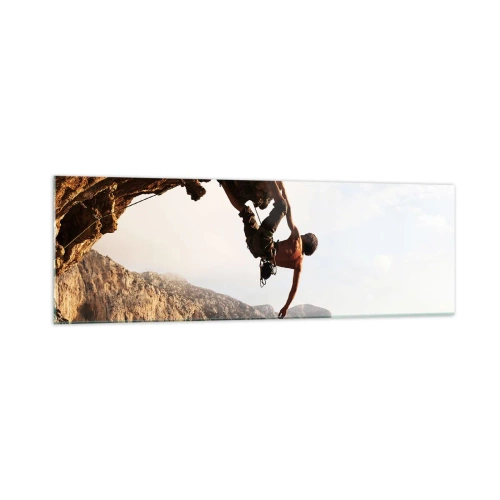 Glasbild - Bild auf glas - Ein Kletterer auf einer steilen Klippe in den Bergen im Sonnenschein - 160x50cm - Die Welt ist in einer Hand auf einem Felsblock geschrumpft - Moderne Wanddekoration für Wohnzimmer und Schlafzimmer ARTTOR