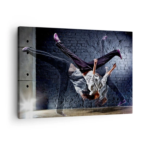 Bild auf Leinwand - Leinwandbild - Eine Tänzerin bei einem dynamischen Sprung gegen eine Ziegelmauer - 70x50cm - Straßenstar - Moderne Wanddekoration für Wohnzimmer und Schlafzimmer ARTTOR