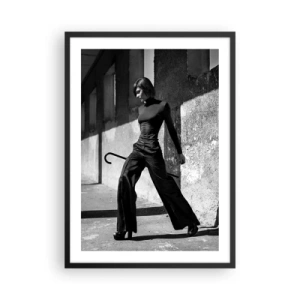 Poster in einem schwarzem Rahmen - Eine Frau in elegantem Outfit mit Gehstock vor dem Hintergrund strenger Architektur - 50x70cm - Urbane Eleganz - Moderne Wanddekoration für Wohnzimmer und Schlafzimmer ARTTOR