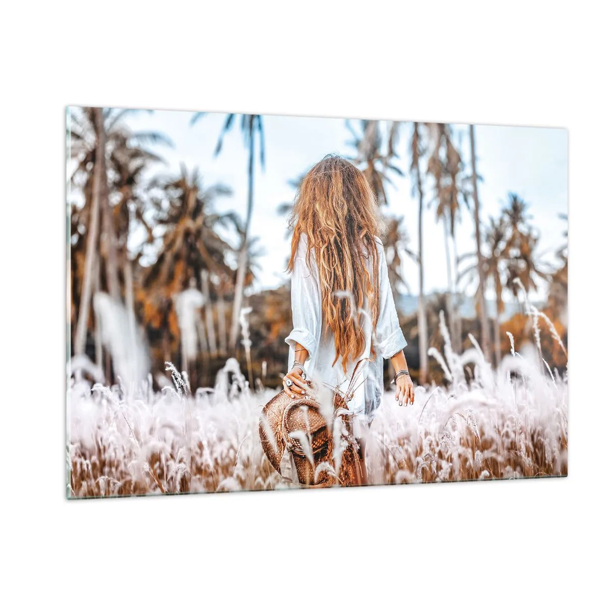 Glasbild - Bild auf glas - Eine Frau im Gras mit einem Hut in der Hand vor einem Hintergrund aus Palmen - 120x80cm - Geboren aus Grasflaum - Moderne Wanddekoration für Wohnzimmer und Schlafzimmer ARTTOR