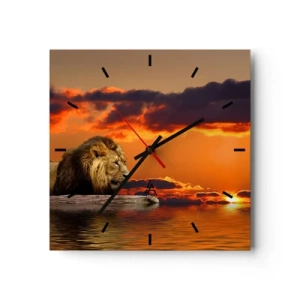 Wanduhr - Glasuhr - Ein Löwe ruht bei Sonnenuntergang vor einem dramatischen Himmel am Wasser. - 30x30cm - König der Natur - Moderne Wanddekoration für Wohnzimmer und Schlafzimmer ARTTOR