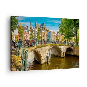 Bild auf Leinwand - Leinwandbild - Ein malerischer Kanal mit einer Brücke in Amsterdam - 70x50cm - Frühling am Kanal - Moderne Wanddekoration für Wohnzimmer und Schlafzimmer ARTTOR