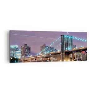 Bild auf Leinwand - Leinwandbild - Brooklyn Bridge bei Nacht mit der beleuchteten Stadt im Hintergrund - 140x50cm - Seit vielen Jahren die Brooklyn Bridge - Moderne Wanddekoration für Wohnzimmer und Schlafzimmer ARTTOR