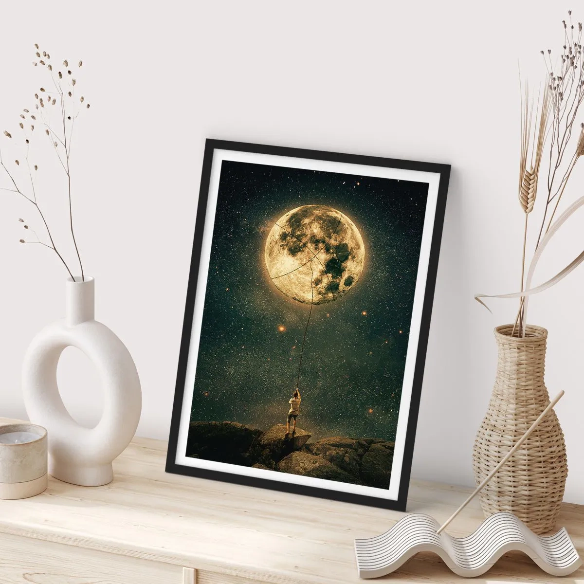 Poster in einem schwarzem Rahmen - Eine Figur, die den Mond an einem Seil in einer Sternenlandschaft hält. - 50x70cm - Der Mann, der den Mond gestohlen hat - Moderne Wanddekoration für Wohnzimmer und Schlafzimmer ARTTOR